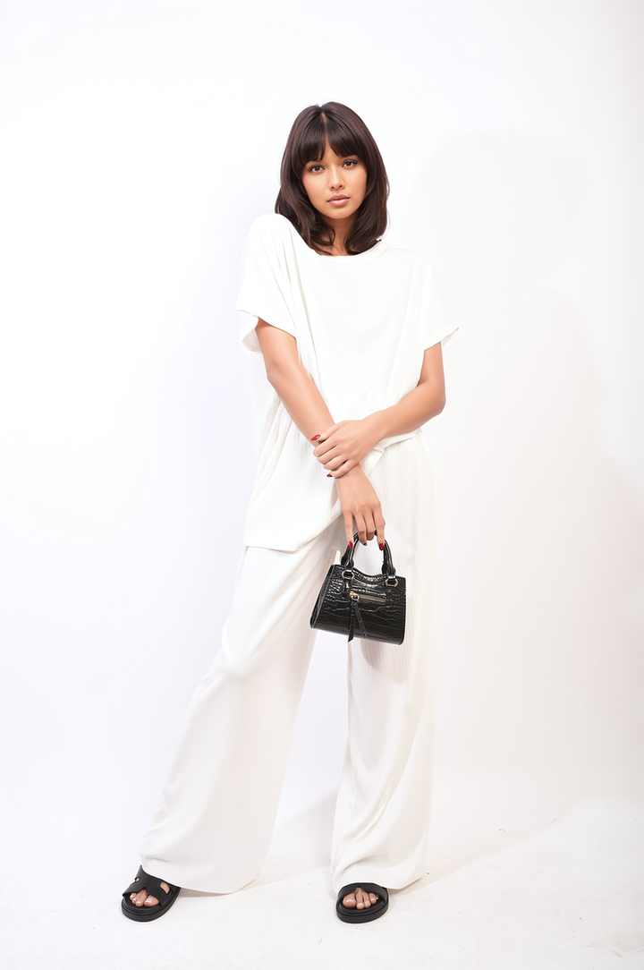 Woman holding a black purse, modeling the Gabriella Oversized Top and Wide Leg Trouser Co-ord Set, showcasing its relaxed, contemporary style.