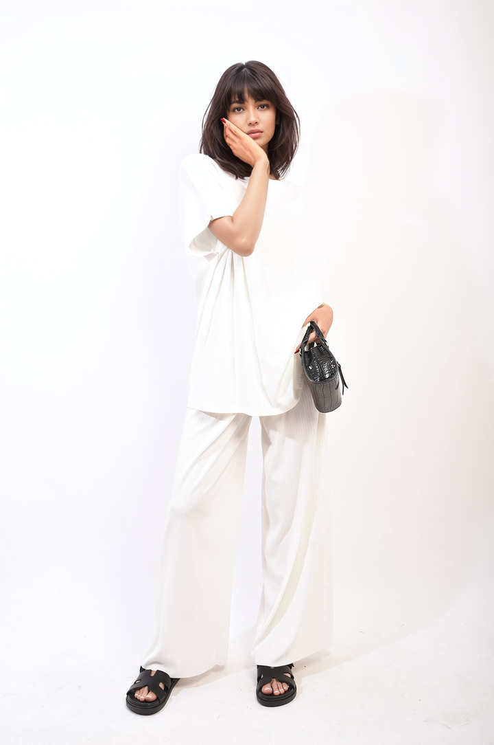 Woman in oversized top and wide leg trouser co-ord set, holding purse, showcasing relaxed elegance and comfort for stylish everyday wear.