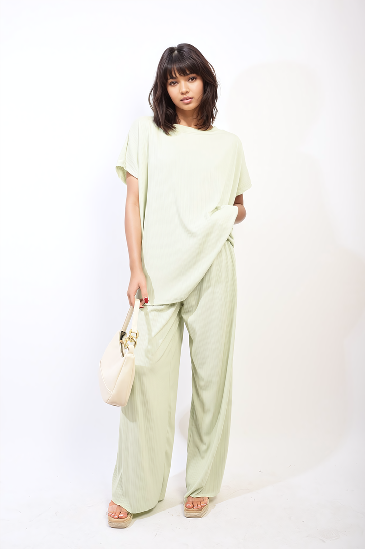 Woman in oversized top and wide leg trouser co-ord set, holding a purse, showcasing relaxed yet chic style at Holiday Clothes UK.