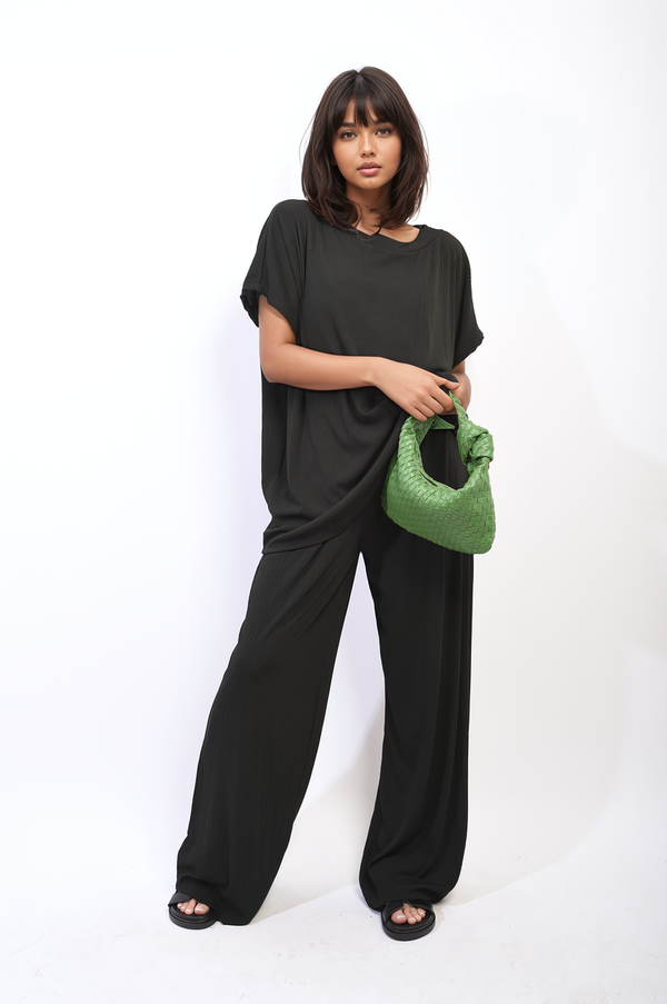 Woman holding a green purse, wearing the Gabriella Oversized Top and Wide Leg Trouser Co-ord Set, showcasing its relaxed and chic style.