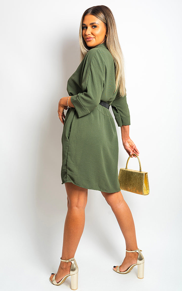 Woman in a green Georgia Collared Button Down Mini Dress holding a gold purse, showcasing the dress's A-line silhouette and collared neckline.