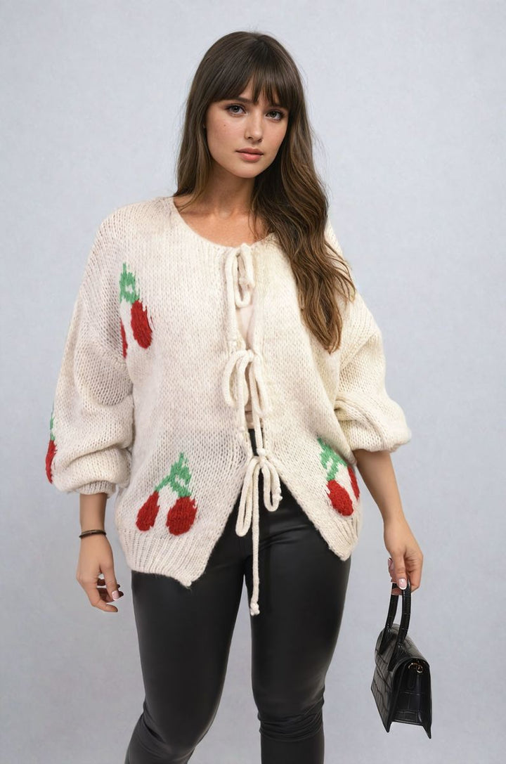 Woman wearing a Giselle Tie Front Cherry Print Knitted Cardigan, showcasing its playful cherry design and tie front detail.