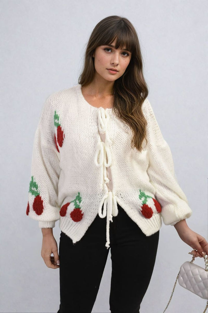 Woman wearing the Giselle Tie Front Cherry Print Knitted Cardigan, showcasing its playful cherry design and tie front detail, epitomizing cozy fashion.