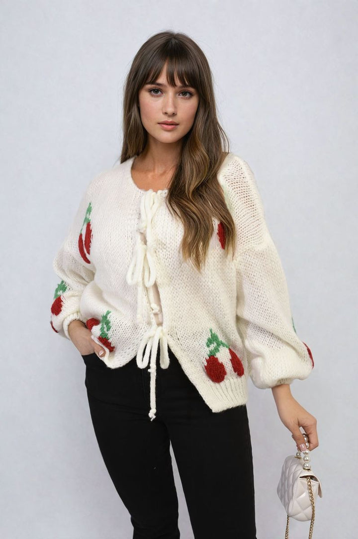 Woman wearing the Giselle Tie Front Cherry Print Knitted Cardigan, showcasing its playful cherry print and tie front, offering a cozy and stylish look.