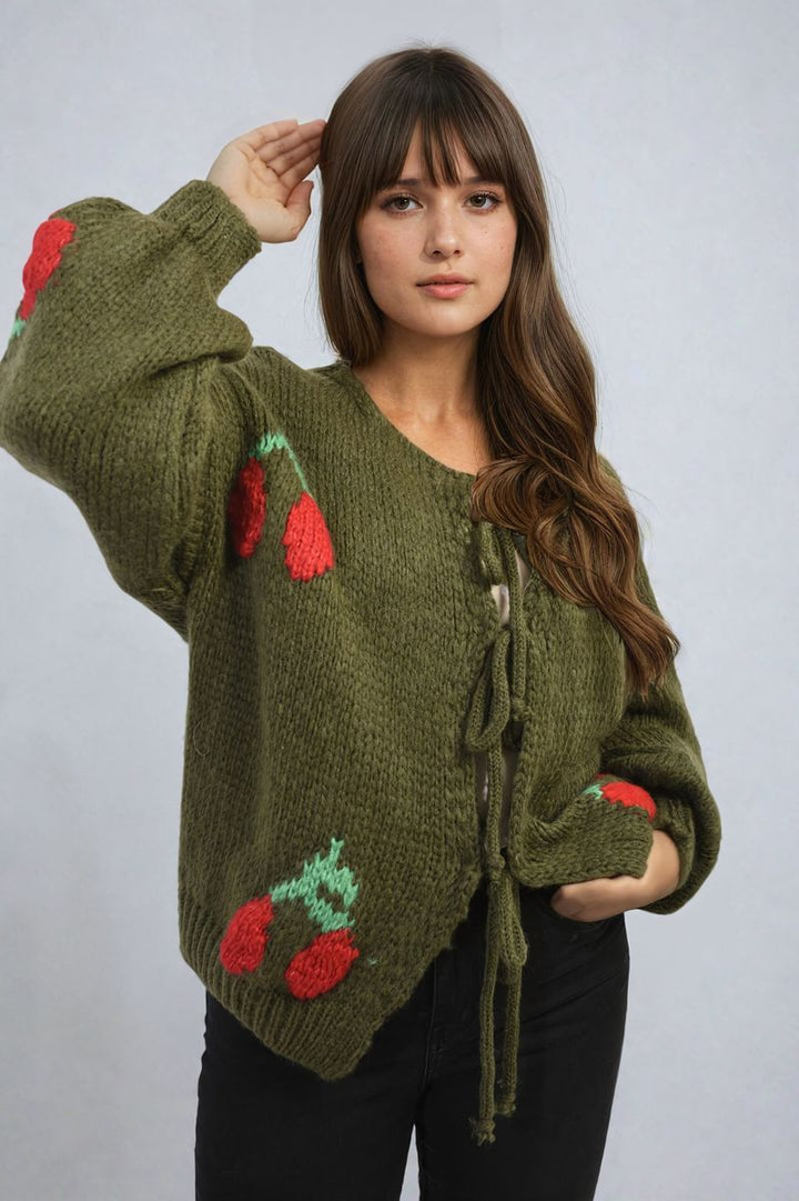 Woman wearing the Giselle Tie Front Cherry Print Knitted Cardigan, featuring a playful cherry pattern and tie front, highlighting cozy knit design.