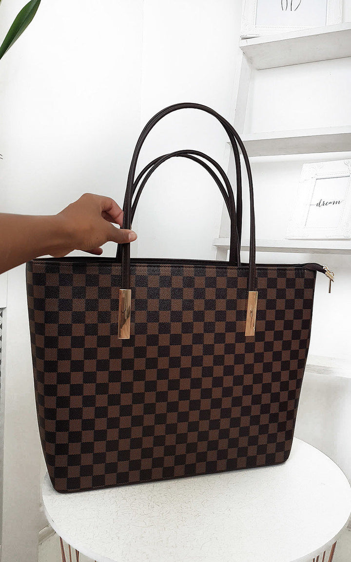 Checked Two in One Handbag being held, featuring a brown and black checkered pattern with a zip closure and detachable inner bag, ideal for day-to-night use.