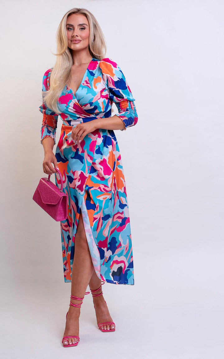 Wrap Front Printed Midi Dress featuring a colorful pattern, worn by a woman with blonde hair, paired with a pink handbag and visible feet.