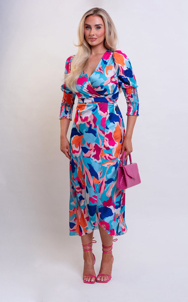 Wrap Front Printed Midi Dress worn by a woman, featuring a colorful pattern and stylish wrap design, complemented by a pink handbag. Ideal for special occasions.