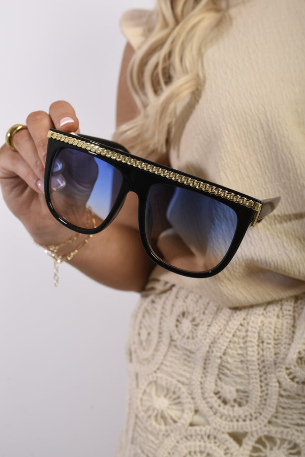 Woman holding Ingrid Square Oversized Sunglasses with Gold Stripe, showcasing their elegant design and sophisticated style, ideal for fashionable holiday and everyday wear.