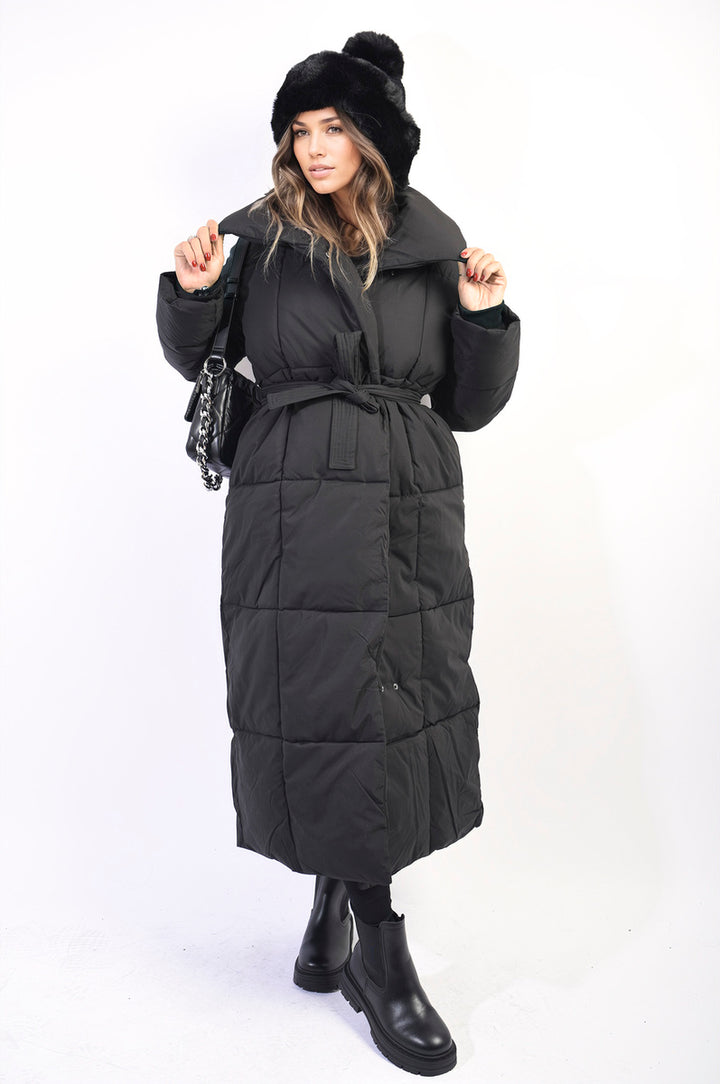 Longline Puffer Jacket with Belt Detail worn by a woman, showcasing its elegant waist-cinching design, ideal for stylish winter wear.