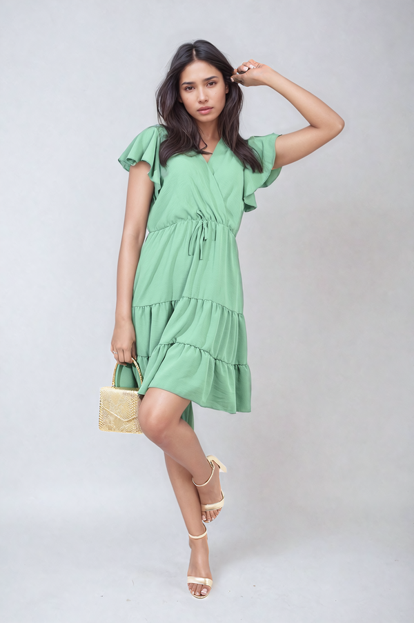 Woman modeling the Ruffle Sleeve Tiered Mini Dress, showcasing its elegant ruffle sleeves and tiered skirt, perfect for stylish holiday outings.