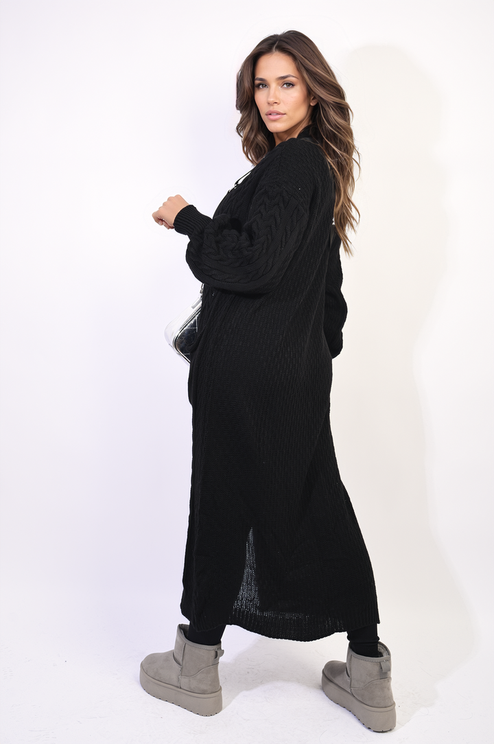 Woman wearing the Front Open Long Knitted Cardigan with Front Pockets, styled with a long black dress and grey boots.