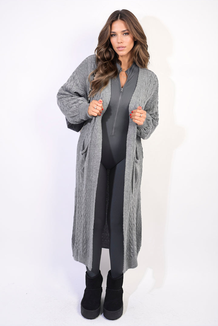 Woman wearing Front Open Long Knitted Cardigan with Front Pockets, styled with a grey sweater and black boots, showcasing cozy, chic fashion.