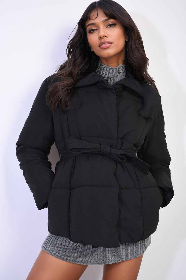 Woman wearing a Quilted Padded Puffer Jacket with Belt Detail, showcasing its quilted design and waist-cinching belt for a stylish winter look.