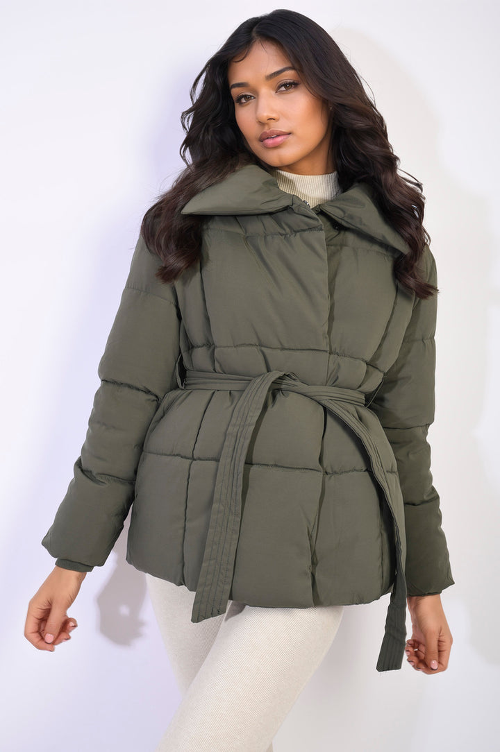 Quilted Padded Puffer Jacket with Belt Detail worn by a woman, showcasing its quilted design and waist-cinching belt for an elegant winter look.