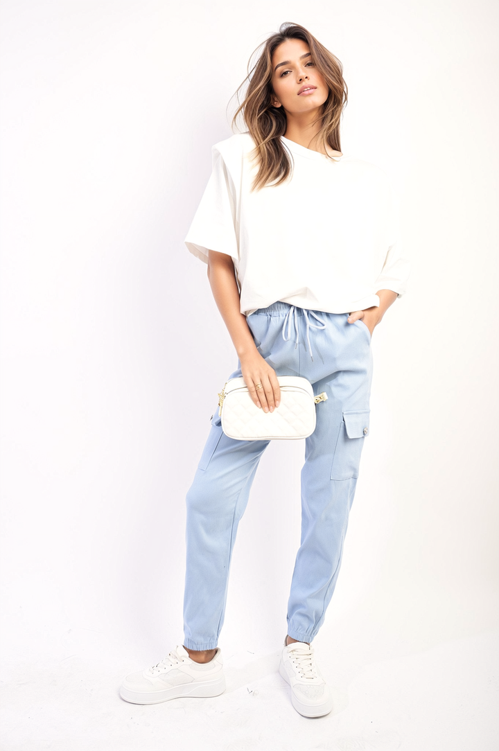 Woman in white shirt and denim holding Janelle Drawstring Waist Cargo Joggers, showcasing its drawstring waist and cargo pockets for style and functionality.