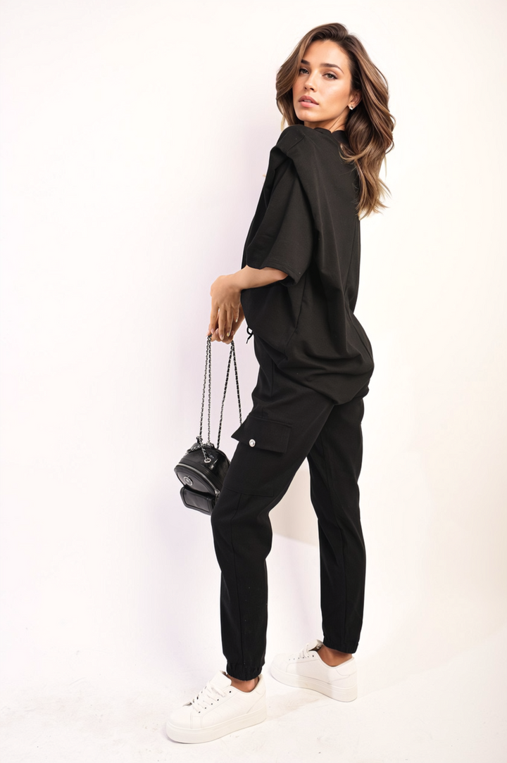 Woman in black outfit modeling Janelle Drawstring Waist Cargo Joggers, showcasing their stylish fit, drawstring waist, and practical cargo pockets.