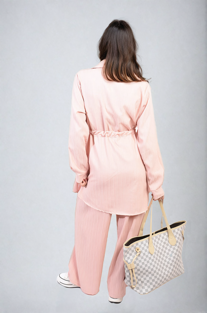 Woman in pink pajamas showcasing the Oversized Long Sleeve Belted Button Down Top and Trouser Co-ord Set, highlighting its relaxed fit and stylish design.