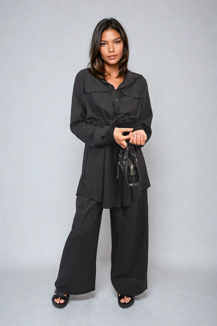 Woman modeling Oversized Long Sleeve Belted Button Down Top and Trouser Co-ord Set, showcasing its stylish, comfortable fit with a black purse accessory.