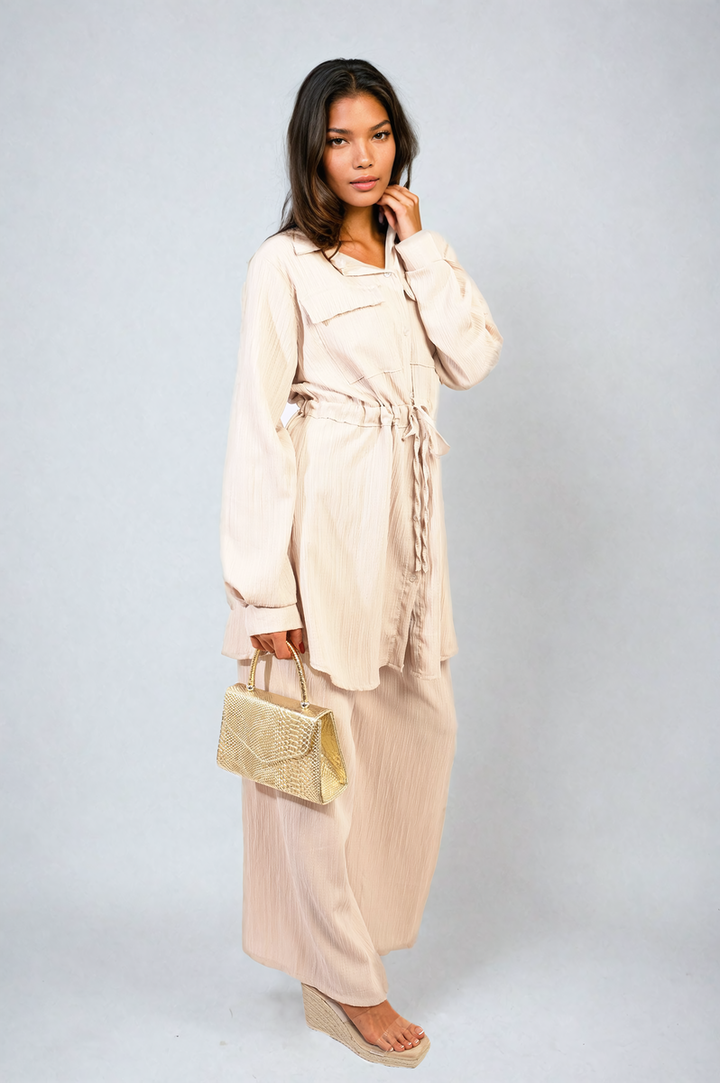 Woman in Oversized Long Sleeve Belted Button Down Top and Trouser Co-ord Set holding a gold purse, showcasing stylish and versatile fashion.