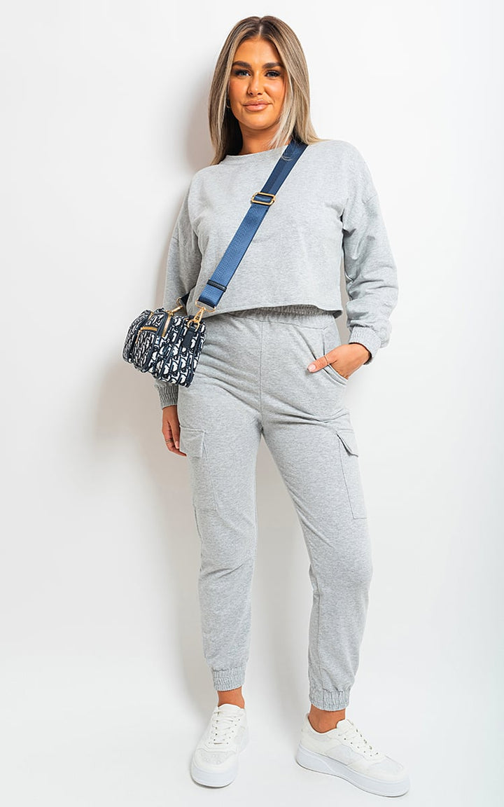 Woman wearing Jessie Cropped Long Sleeve Top and Cargo Joggers Co-ordinates, posing stylishly with a blue and black bag and white sneakers.