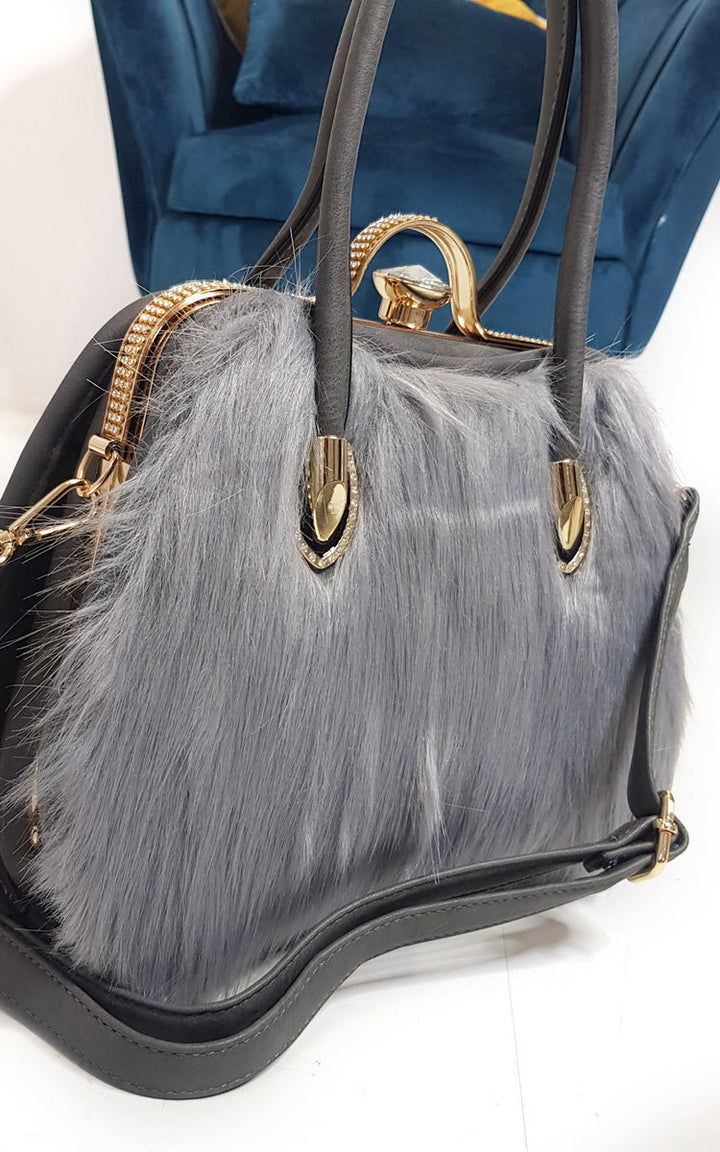 Faux Fur Handbag with grey faux fur front, black faux leather back, and gold diamante clip fastening. Perfect accessory for winter outfits.