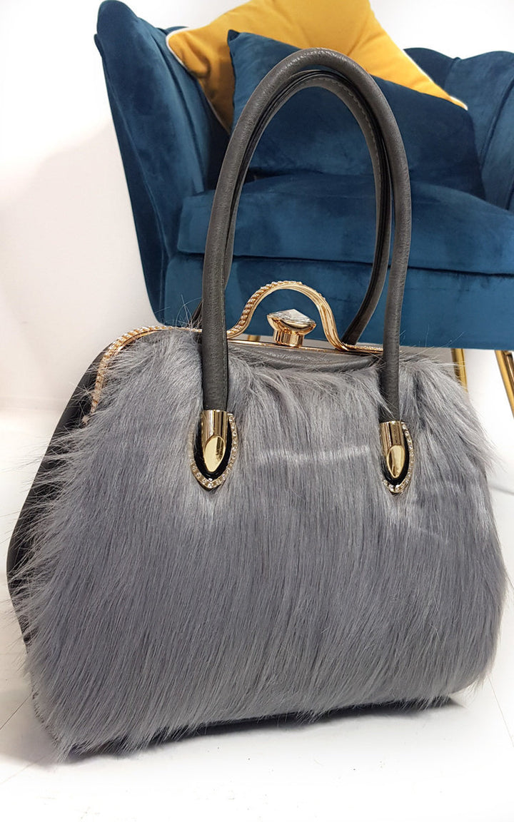 Faux Fur Handbag with gold diamante clip and leather straps, showcasing a stylish grey and gold design, perfect for pairing with winter coats.