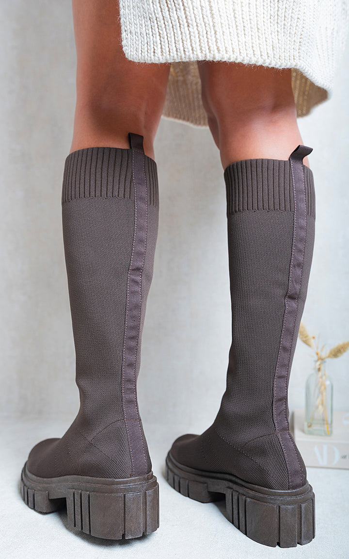 Person wearing Jillian Knee High Chunky Sock Boots, showcasing knee-high elegance and chunky heel chic, perfect for versatile styling and comfort.