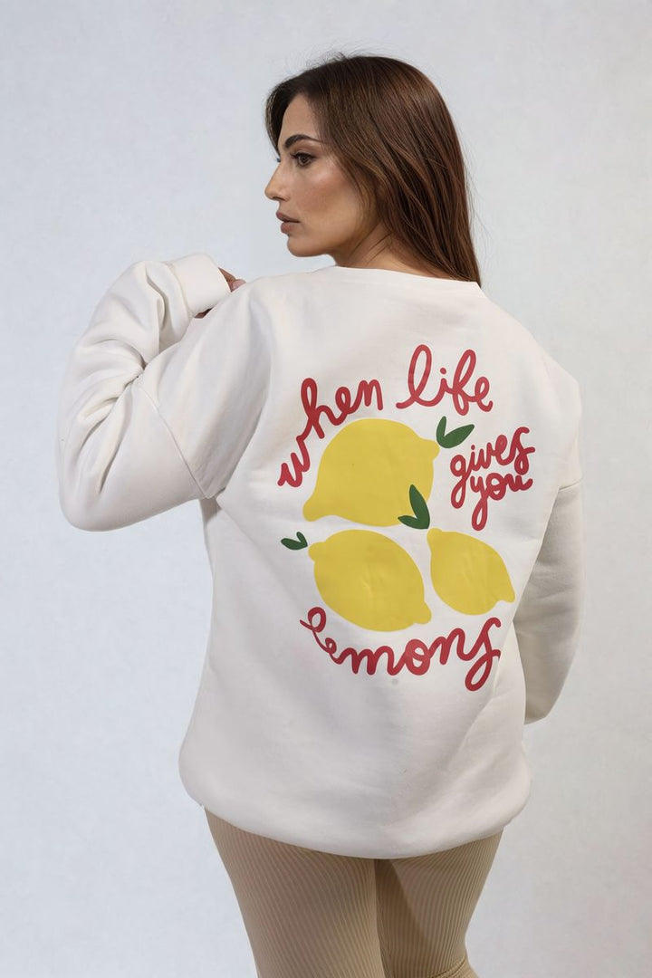 Woman wearing the Lemon Graphic Long Sleeve Knitted Jumper, featuring a cheerful lemon design, ideal for adding a stylish touch to casual holiday outfits.