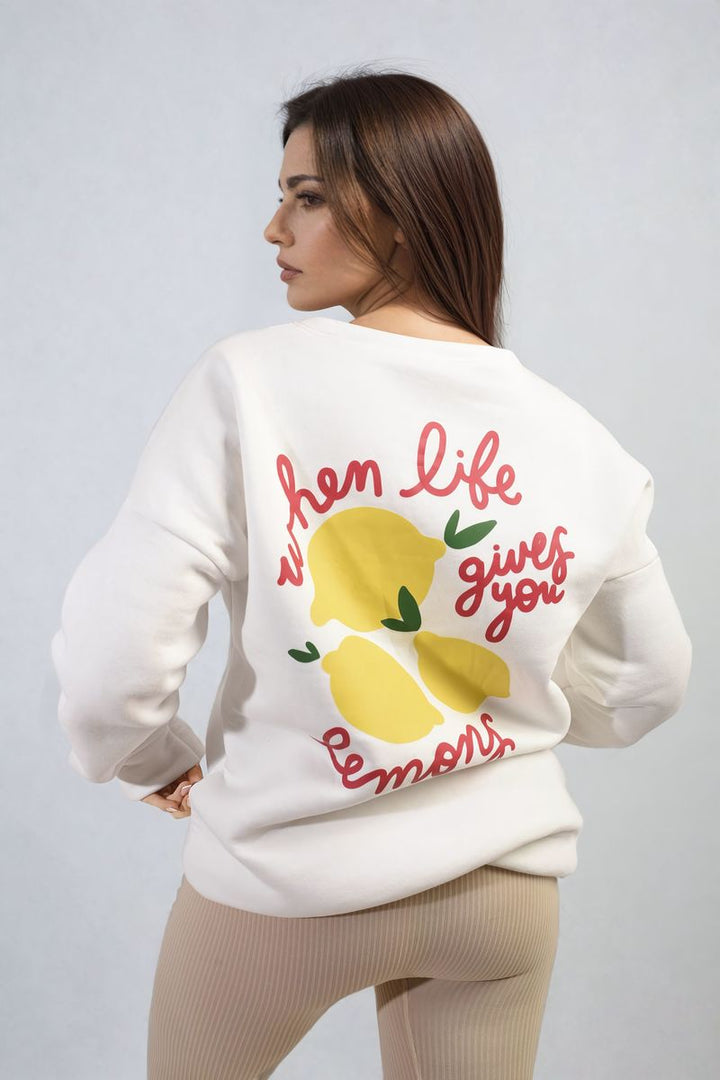 Woman wearing the Joyce Lemon Graphic Long Sleeve Knitted Jumper, featuring a cheerful lemon design, perfect for adding zest to any outfit.