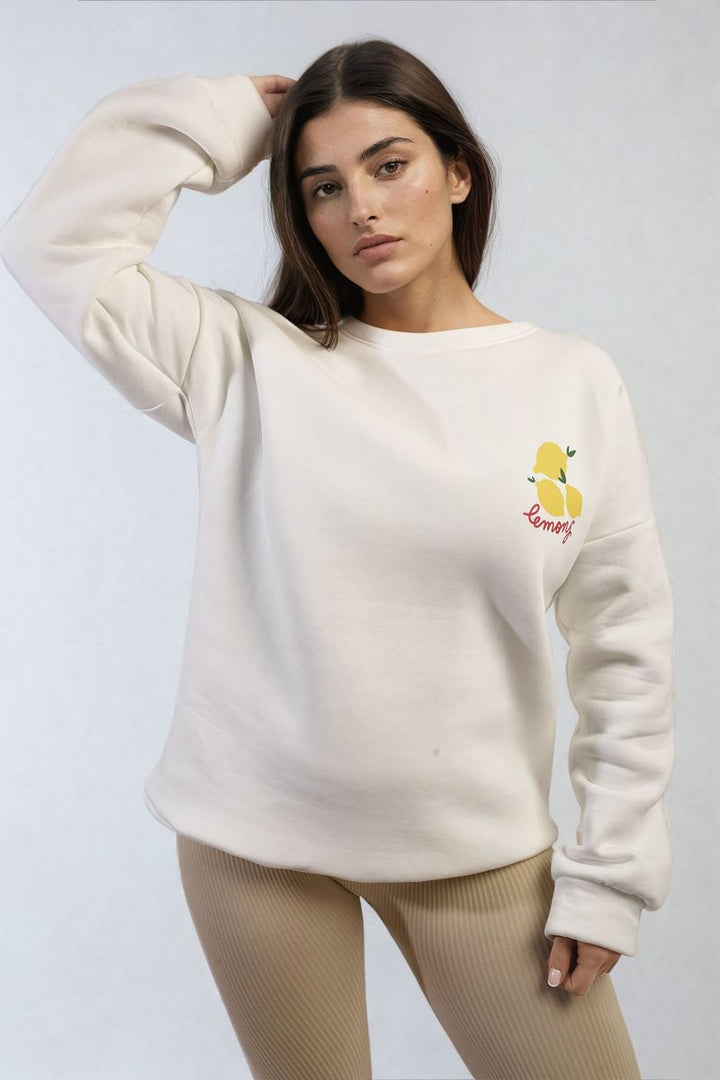 Woman modeling the Joyce Lemon Graphic Long Sleeve Knitted Jumper, showcasing its cozy, stylish design with a cheerful lemon graphic, perfect for a trendy, casual look.