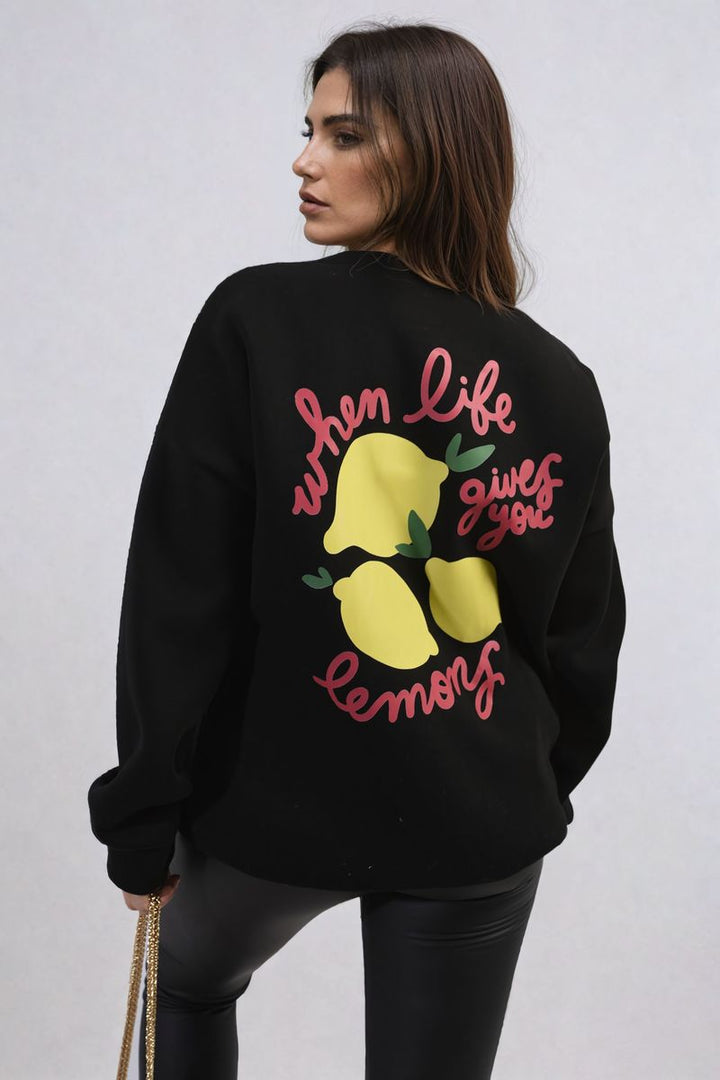 Woman wearing the Joyce Lemon Graphic Long Sleeve Knitted Jumper, featuring a cheerful lemon design, ideal for a cozy and stylish everyday look.