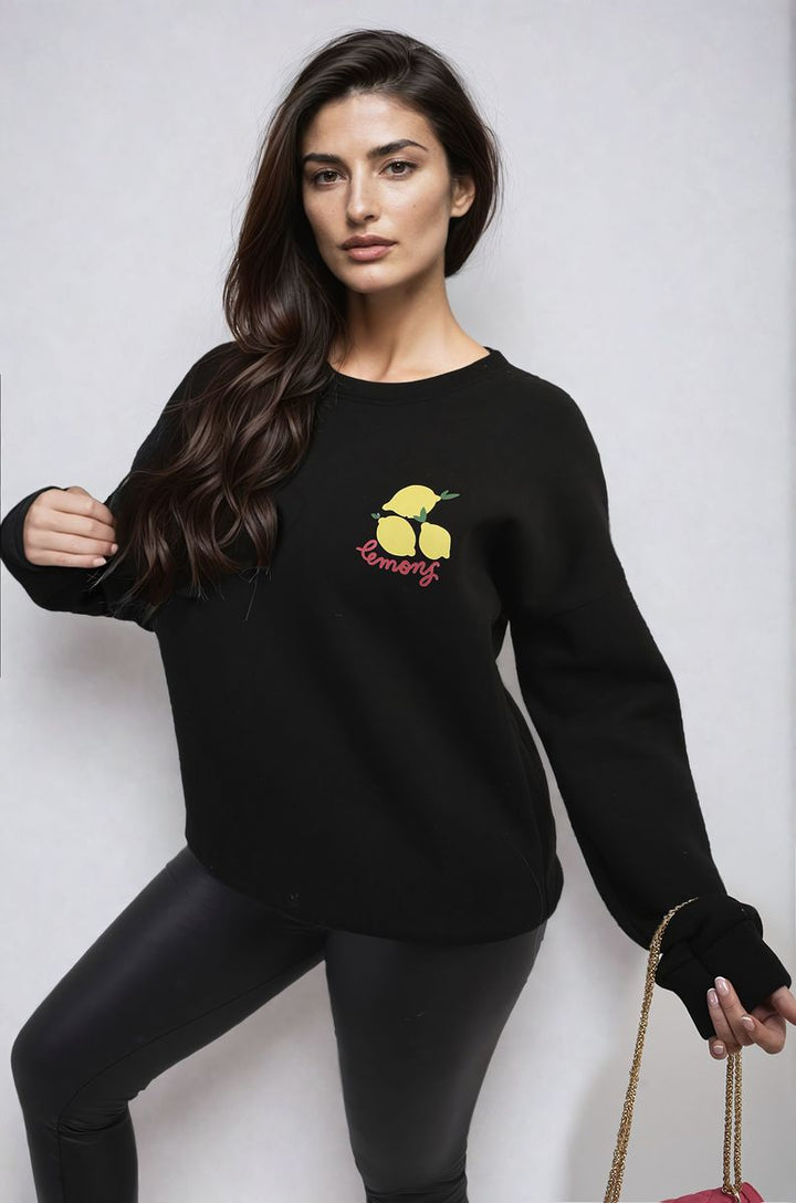 Woman modeling the Joyce Lemon Graphic Long Sleeve Knitted Jumper, showcasing a fun lemon design, perfect for adding zest to casual outfits.