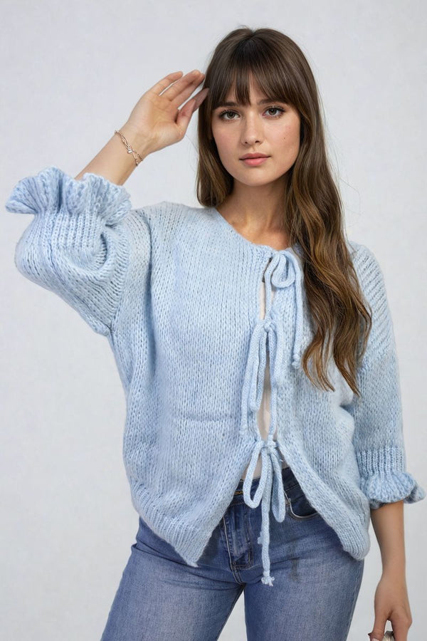 Woman wearing the Juliana Tie Front Detail Chunky Knit Jumper, saluting with one hand, showcasing its stylish tie front design and cozy knit texture.