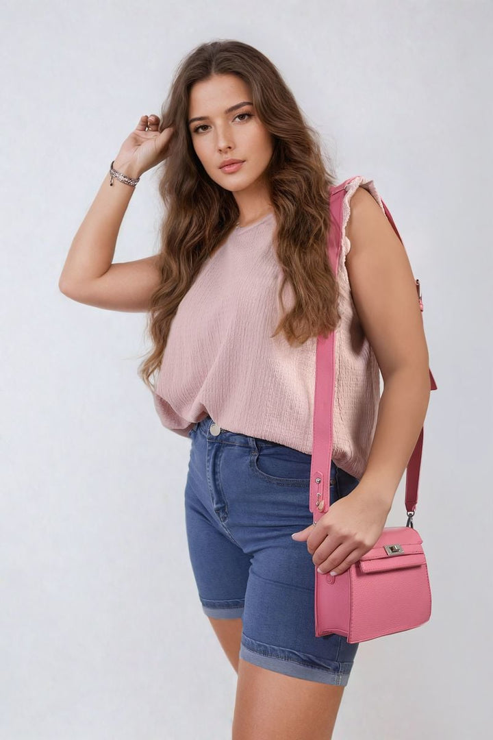 Woman holding a pink purse, wearing Amelia Highwaisted Roll Up Hem Shorts, showcasing their flattering high-waisted fit and stylish roll-up hem.