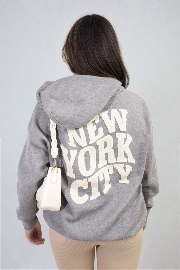 Woman wearing a New York City Print Knitted Hoodie, showcasing its casual style and NYC text design, ideal for relaxed, everyday wear.