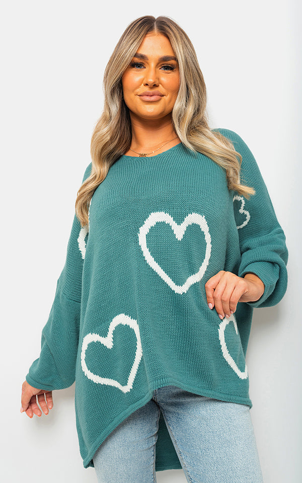 Woman wearing the Knitted Oversized Heart Prints Jumper, featuring white heart patterns on a green sweater, showcasing its cozy and stylish design for cooler seasons.