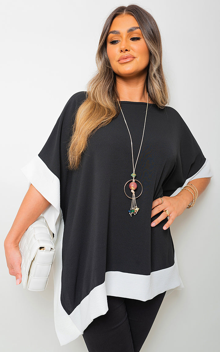 Woman wearing Oversized Contrast Hem Flare Sleeve Top, showcasing its flared sleeves and relaxed fit, accessorized with a white purse and green bead necklace.