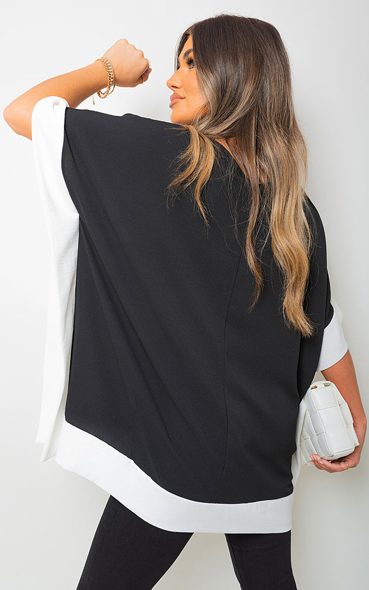 Woman wearing an Oversized Contrast Hem Flare Sleeve Top, showcasing its flared sleeves and relaxed fit, ideal for stylish holiday and everyday wear.