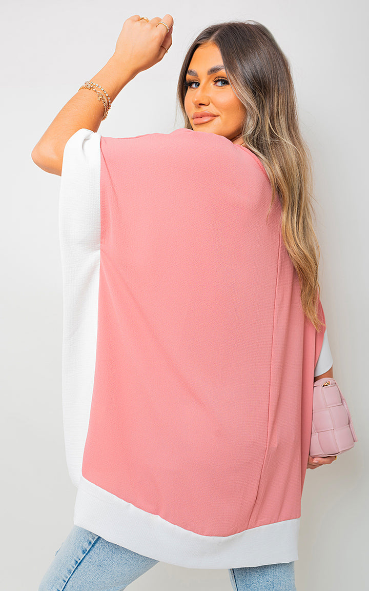 Woman modeling the Oversized Contrast Hem Flare Sleeve Top, showcasing its elegant flared sleeves and unique hem detail, embodying contemporary style and comfort.