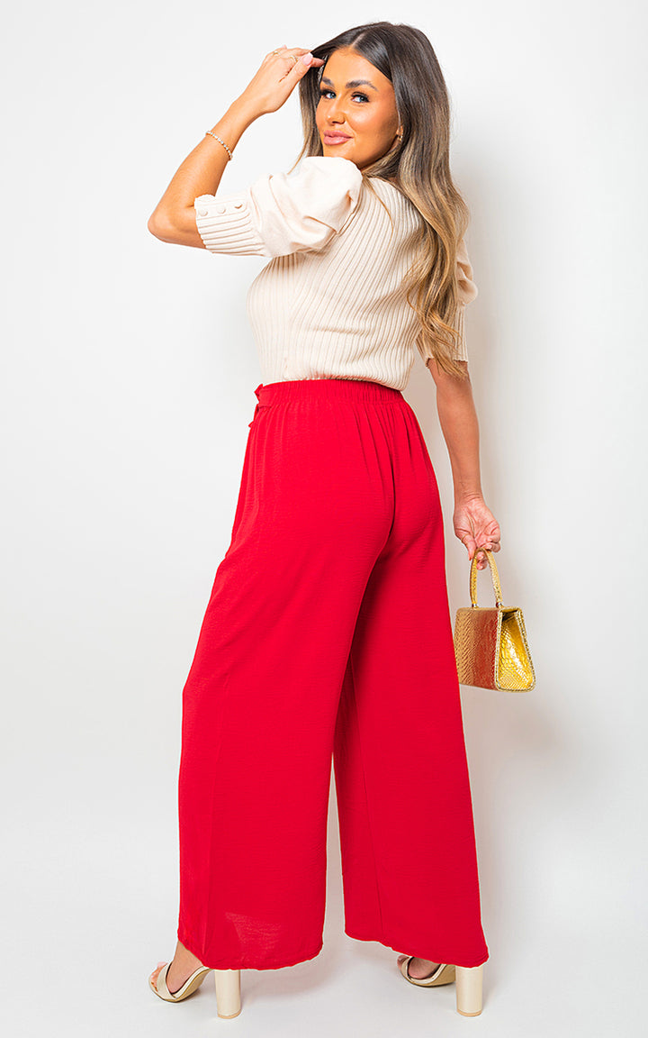 Woman wearing drawstring waist wide leg trousers, showcasing elegant and relaxed fit, holding a purse, exemplifying chic comfort from Holiday Clothes UK.