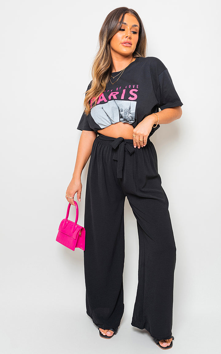 Woman models black drawstring waist wide leg trousers, showcasing a chic, comfortable fit perfect for versatile styling from Holiday Clothes UK.