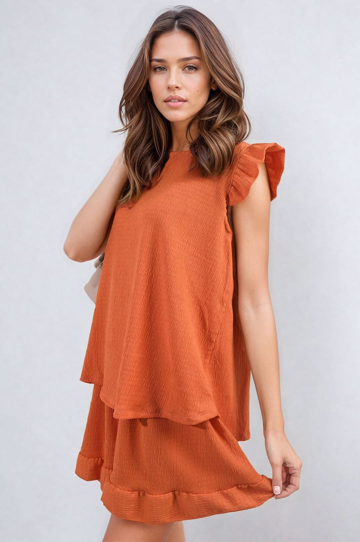 Woman wearing the Layla Ruffle Trim Sleeve Top and Shorts Co-ord Set, showcasing its elegant ruffle sleeves and high-waisted shorts. Perfect for stylish summer outings.