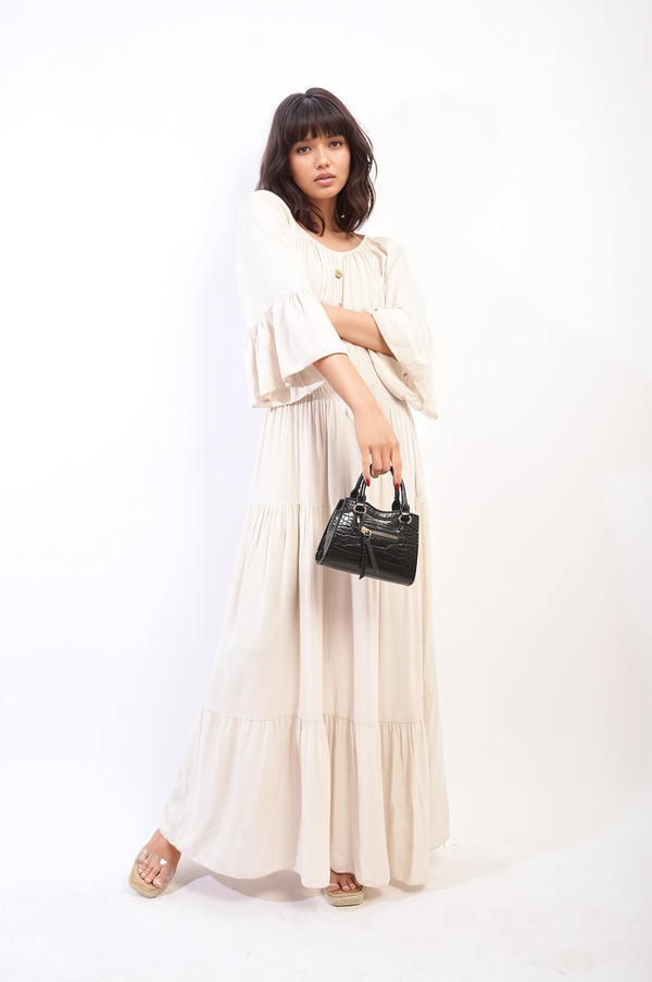 Woman in Ruffle Hem Sleeve Shirred Waist Tiered Maxi Dress holding a black purse, showcasing elegant, flowing design and romantic ruffle sleeves.