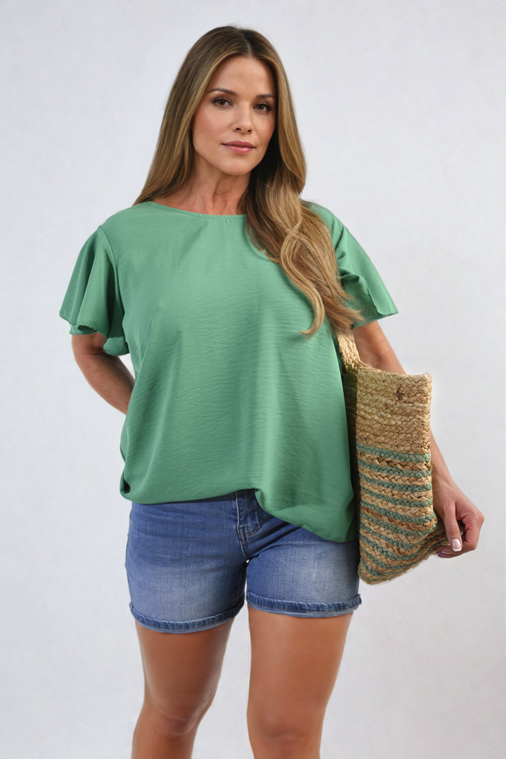 Woman in a green Ruffle Short Sleeve Top holding a straw bag, showcasing a stylish and comfortable holiday look from Holiday Clothes UK.