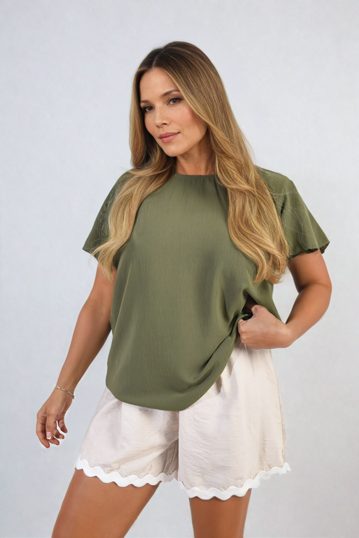 Woman modeling Leilani Ruffle Short Sleeve Top, featuring playful ruffled sleeves and a chic silhouette, ideal for casual outings or dressy occasions.