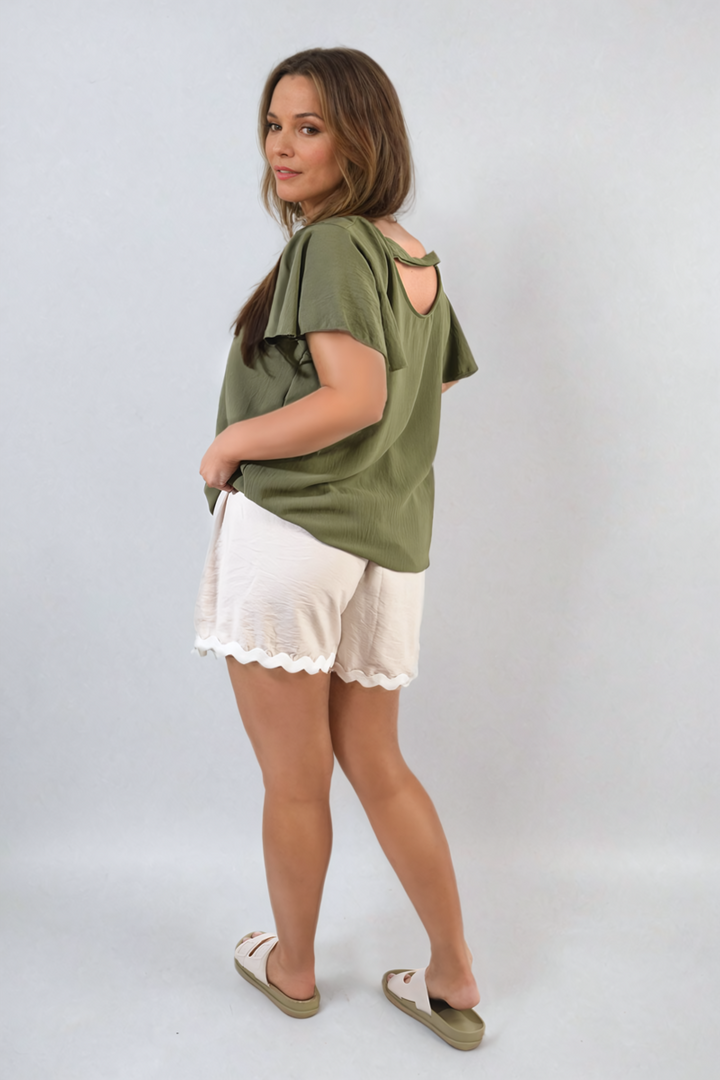 Woman wearing the Leilani Ruffle Short Sleeve Top, showcasing its stylish ruffled sleeves and comfortable fit, ideal for holiday and everyday wear.