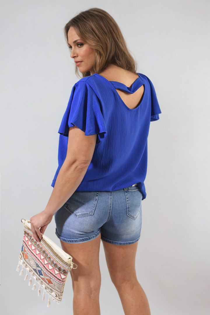 Woman wearing Leilani Ruffle Short Sleeve Top, holding a handbag, showcasing the stylish and feminine ruffled sleeves perfect for casual or dressy occasions.