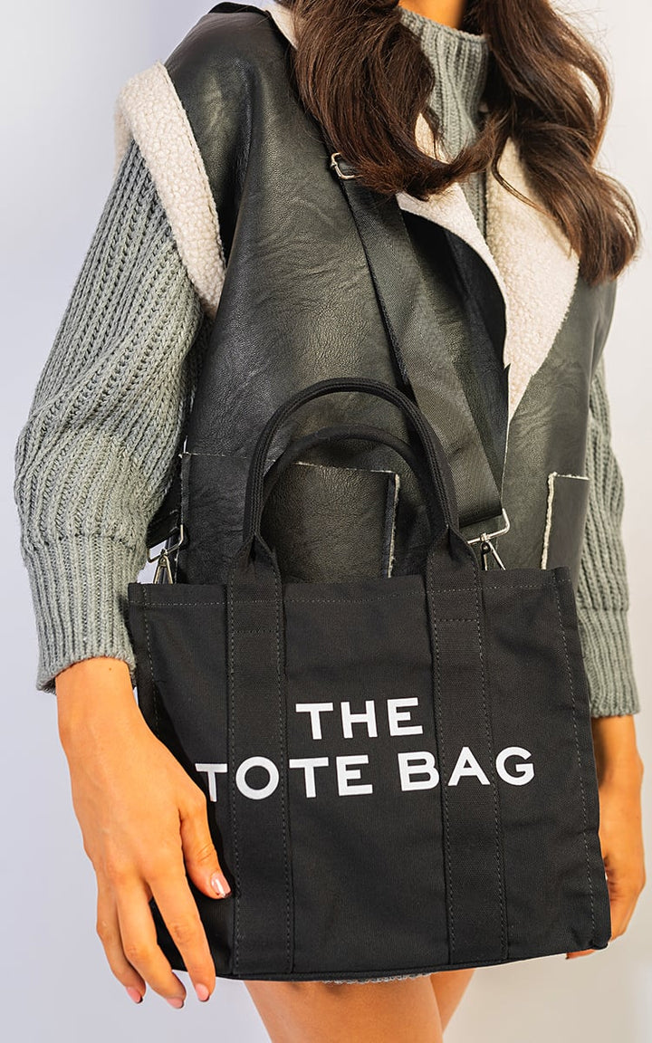 Woman holding the Letter Pattern Canvas Shoulder Shopper Tote Bag, showcasing its stylish design and practicality for everyday use.