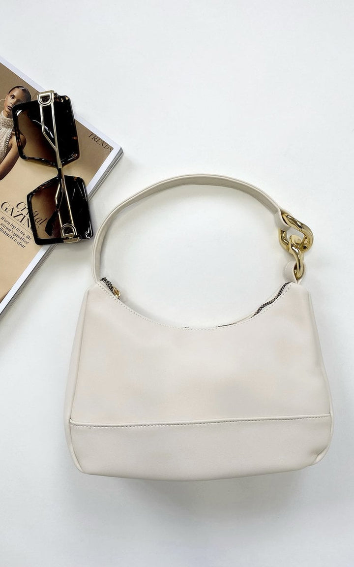 White Lindsey Handbag with Chain Detail, accompanied by sunglasses, showcases a stylish faux leather design ideal for special occasions or nights out.